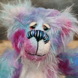 Tim Pimpling is a happy, little one of a kind, mohair artist bear by Barbara-Ann Bears. Tim stands 6.5 inches( 16 cm) tall and is 5 inches ( 13 cm) sitting. He is mostly made from a medium length, slightly distressed and fluffy mohair that Barbara has hand dyed in sky blue with some splashes of magenta, pink and lilac